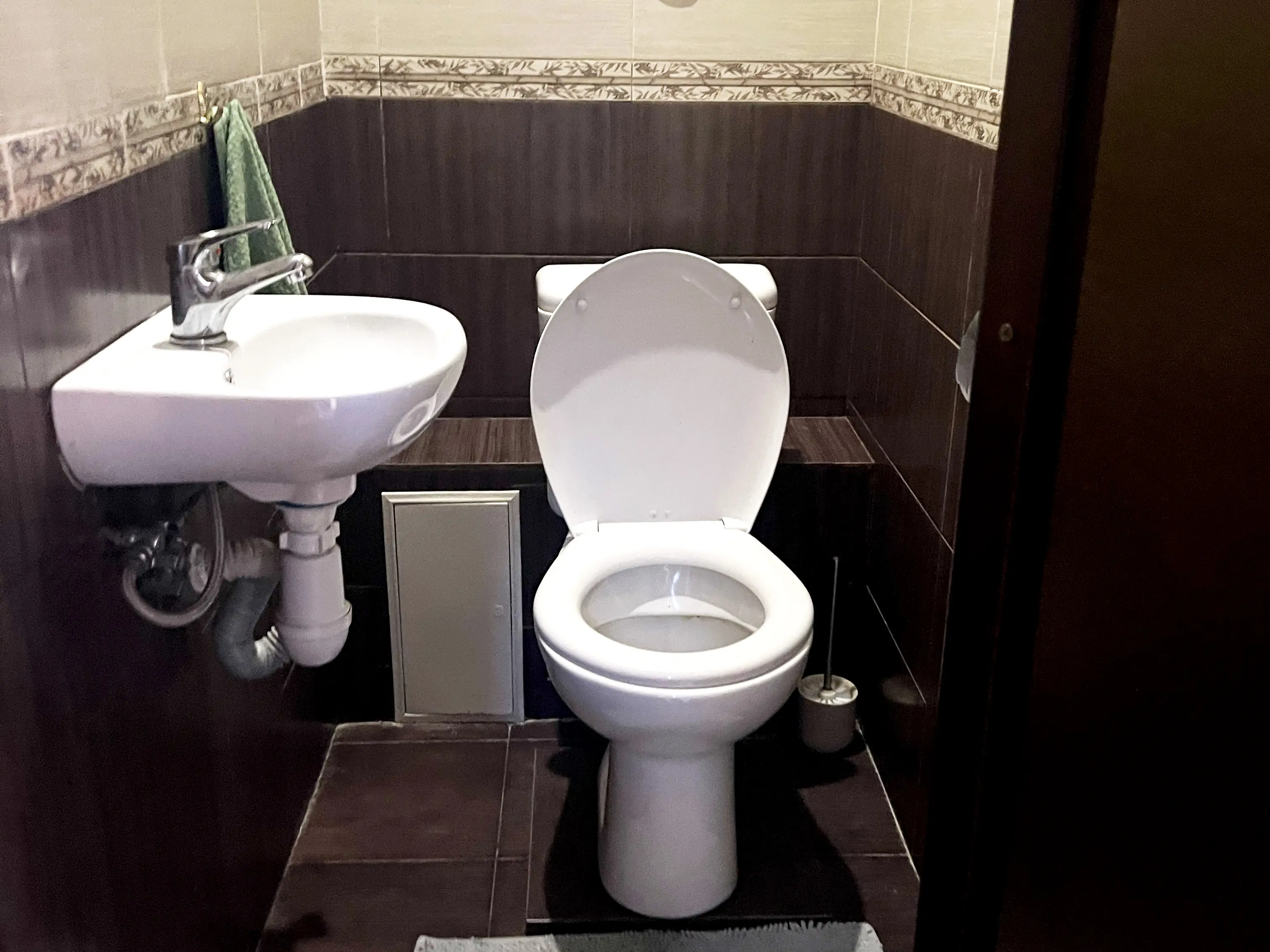 Туалет с небольшой раковиной на первом этаже у входа в коридоре