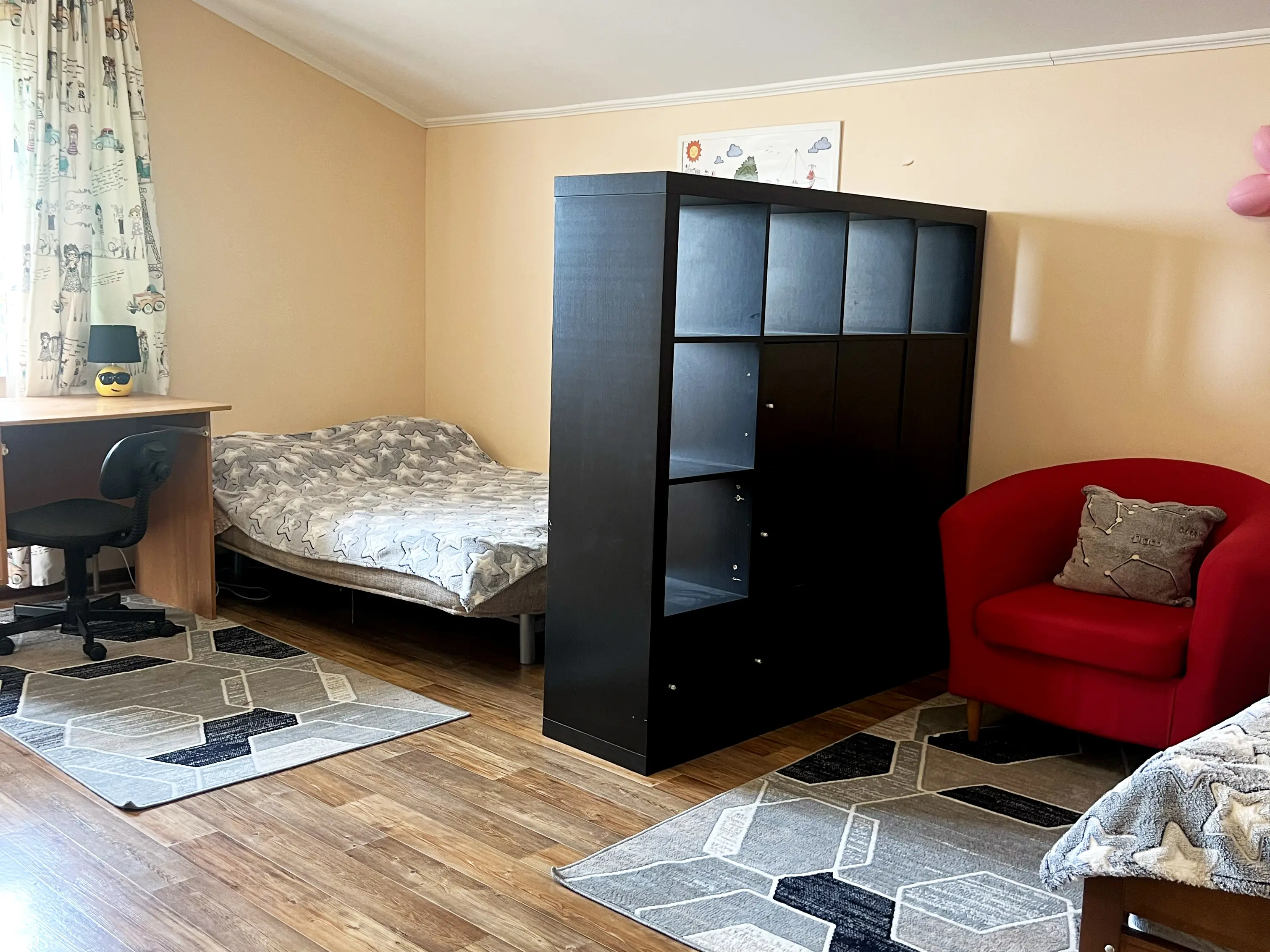 В комнате рабочий стол и двухспальная кровать отделены закрытым стелажом